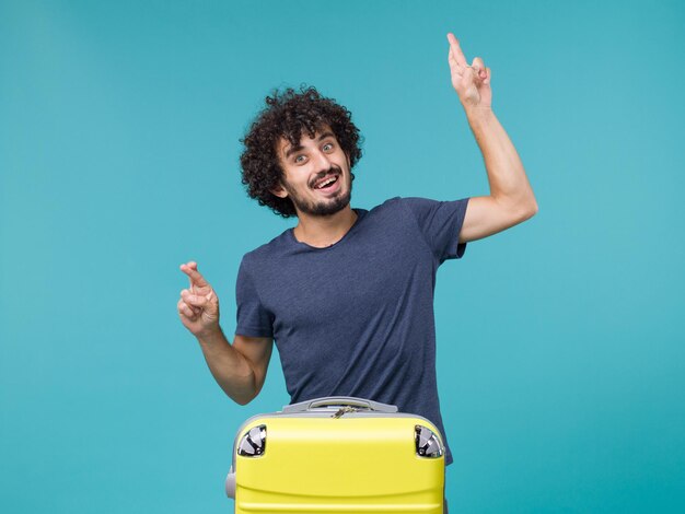 homme en vacances avec valise jaune sur bleu