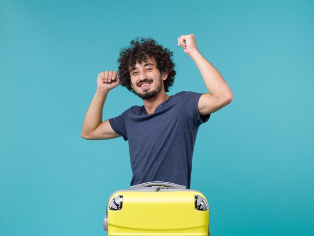 homme en vacances avec valise jaune se sentant heureux sur bleu