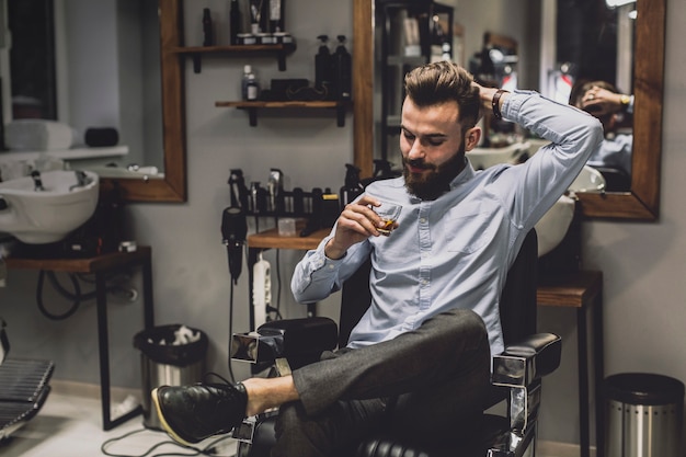 Homme avec un verre d&#39;alcool dans le salon de coiffure