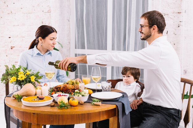 Homme versant du vin dans un verre en dînant en famille
