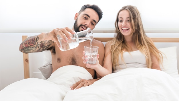 Photo gratuite homme versant de l'eau dans un verre pour sa femme dans la chambre