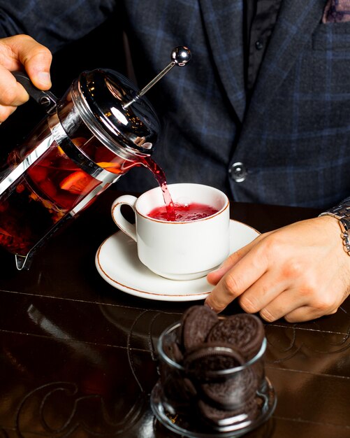 L'homme verse du thé aux fruits dans la tasse