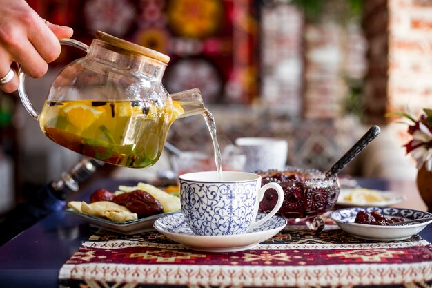 Homme, verse, thé, dans, tasse, confiture, bonbons, vue côté