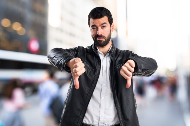 Un homme avec une veste en cuir faisant un mauvais signal