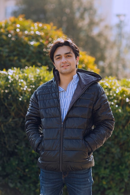 Photo gratuite homme en veste noire debout dans le parc et attendant quelqu'un. photo de haute qualité