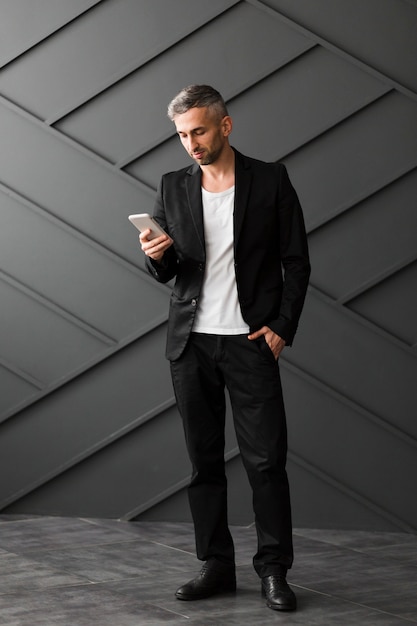 Homme, à, veste noire, debout, et, utilisation, sien, téléphone