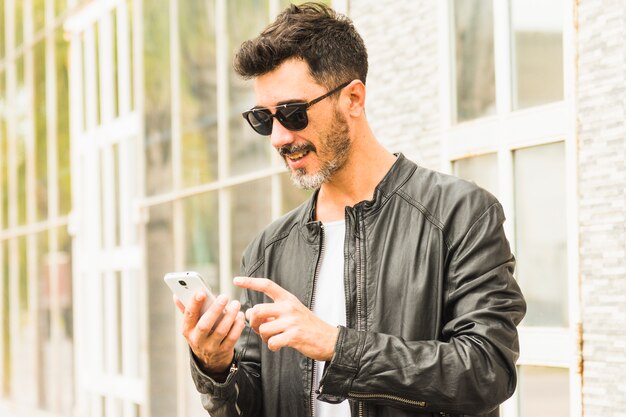 Homme en veste noire, lunettes de soleil à l&#39;aide de téléphone portable