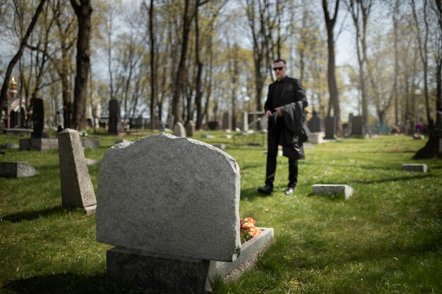Un homme visite une pierre tombale au cimetière.