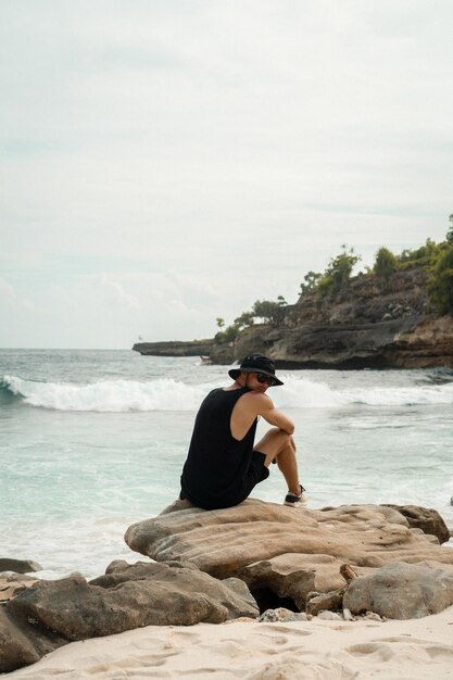 Homme voyageur sur un rocher au bord de l'océan.