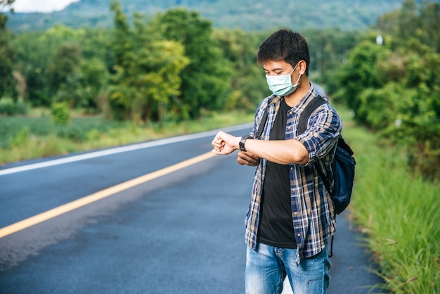 Un homme voyageur avec un sac à bandoulière et regardant sa montre.