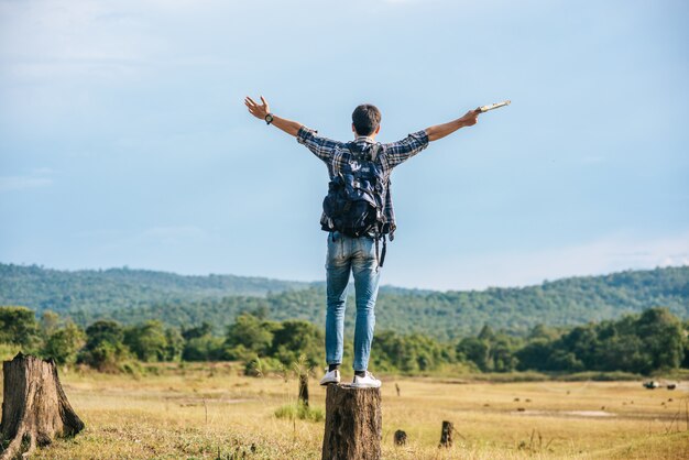 Un homme voyageur avec un sac à dos, portant une carte et debout sur une souche d'arbre