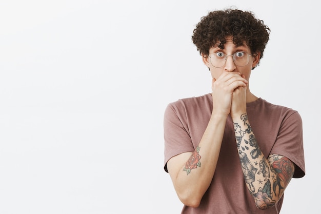 Homme voyant ami faire un truc cool sur le skate haletant regardant étonné et surpris couvrant la bouche avec les mains sautant les yeux debout impressionné et choqué sur le mur gris