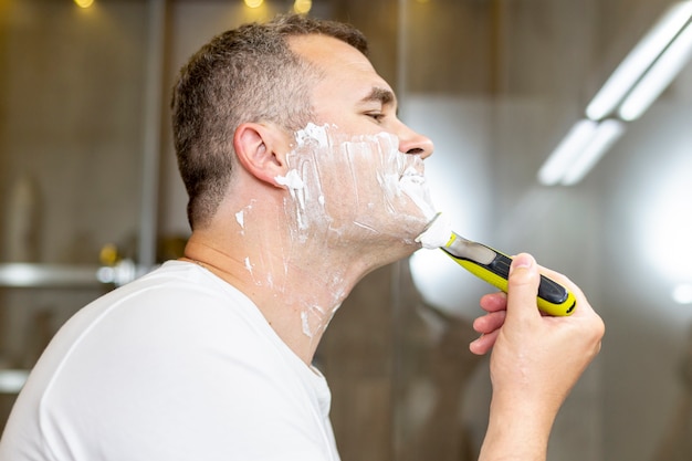 Photo gratuite homme vue de côté se raser dans la salle de bain
