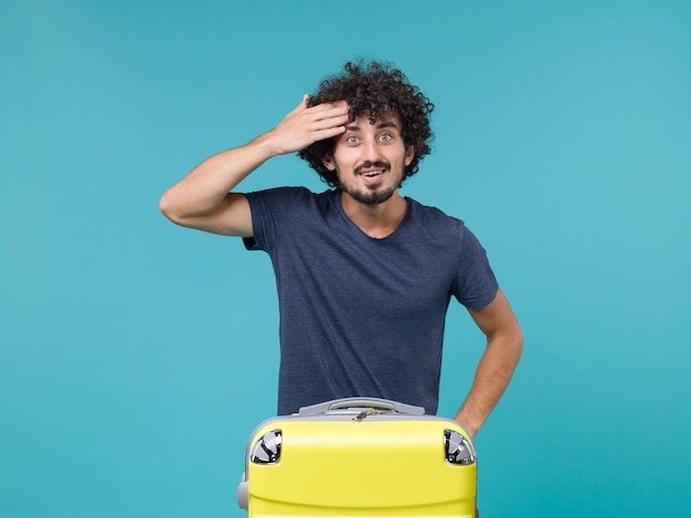 Homme vue de face en vacances avec sac jaune sur bleu