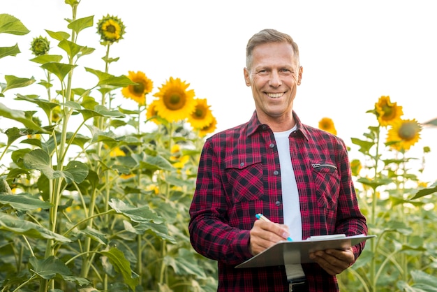 Homme de vue moyenne avec un presse-papier dans un champ