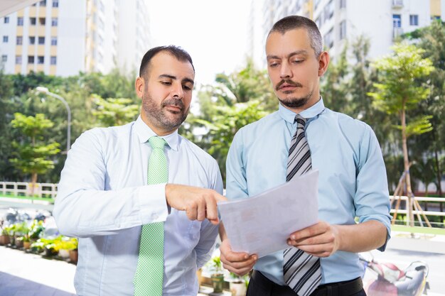 Hommes d&#39;affaires concentrés discutant d&#39;un rapport en marchant