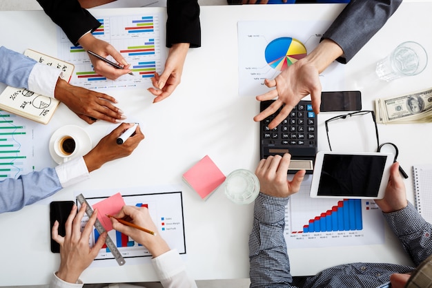 hommes d'affaires mains sur tableau blanc avec des documents et des projets