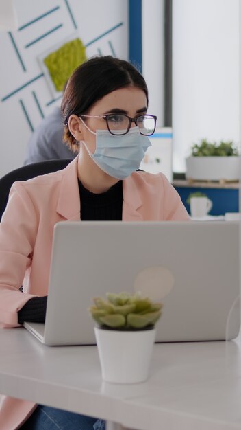 Hommes d'affaires avec des masques médicaux travaillant ensemble dans un nouveau bureau normal pendant la pandémie de coronavirus...