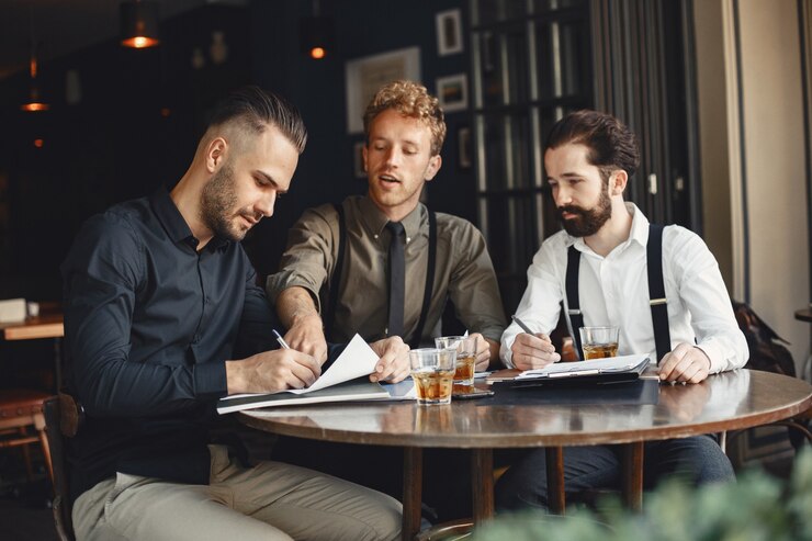 Photo gratuit hommes d'affaires en négociations. les hommes avec de l'alcool assis à la table. des amis parlent.