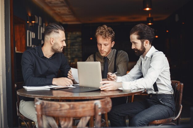 Hommes d'affaires en négociations. Des hommes barbus assis à table, des amis parlent.