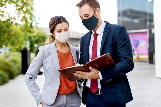 Hommes d'affaires portant des masques médicaux discutant du plan de travail pendant la pandémie de coronavirus
