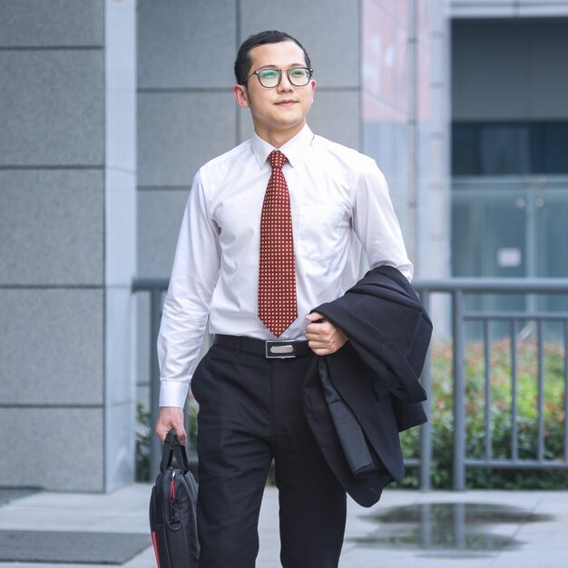 Les hommes d&#39;affaires portent des ordinateurs portables pour travailler à l&#39;entrée d&#39;un immeuble de bureaux