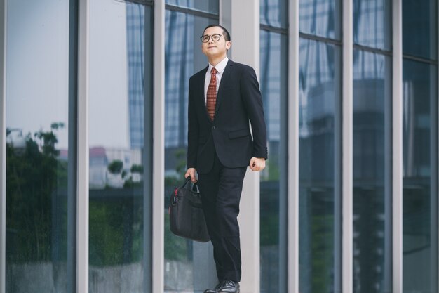 Les hommes d&#39;affaires portent des ordinateurs portables pour travailler à l&#39;entrée d&#39;un immeuble de bureaux