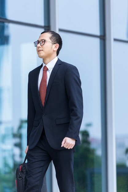 Les hommes d&#39;affaires portent des ordinateurs portables pour travailler à l&#39;entrée d&#39;un immeuble de bureaux