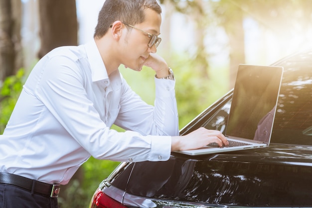 Les hommes d&#39;affaires travaillent avec des ordinateurs portables sur le côté de la voiture