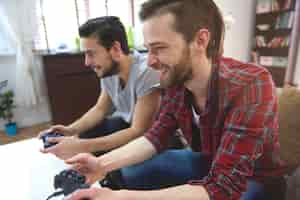 Photo gratuite hommes affectueux jouant à la playstation dans le salon