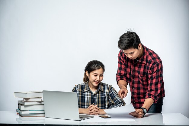 Les hommes apprennent aux femmes à travailler avec des ordinateurs portables au travail.