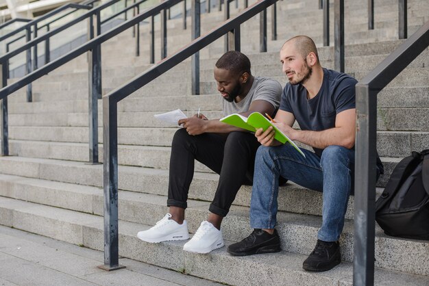 Hommes assis sur les escaliers tenant des cahiers