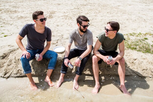 Les hommes aux pieds nus discutant sur la plage de sable fin