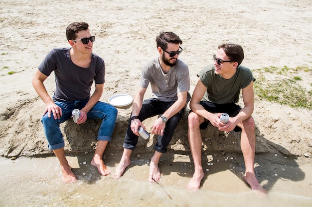 Les hommes aux pieds nus discutant sur la plage de sable fin