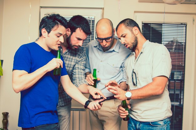 Hommes avec de la bière et des smartphones dans la fête