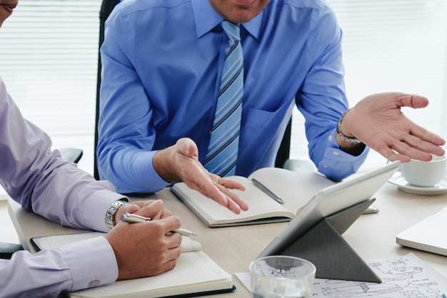 Hommes cultivés discutant du rapport annuel à l'aide d'une tablette numérique