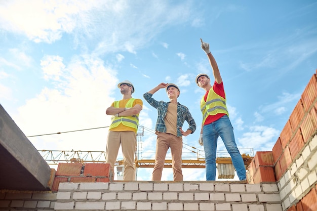 Hommes debout sur le mur de briques du bâtiment en construction