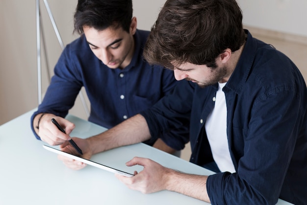 Hommes discutant des données sur une tablette