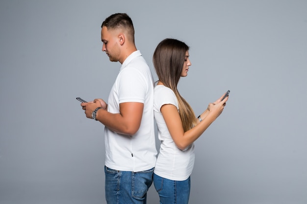 Hommes et femme couple debout avec des téléphones mobiles de marque dans leurs mains isolés sur fond gris