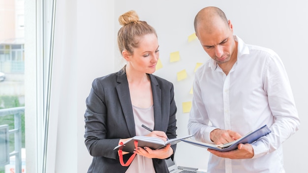 Hommes et femmes d&#39;affaires regardant le calendrier dans le journal