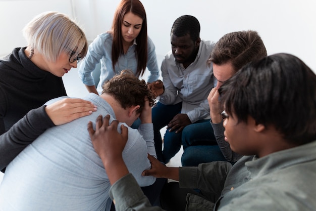 Des hommes et des femmes consolent un patient triste