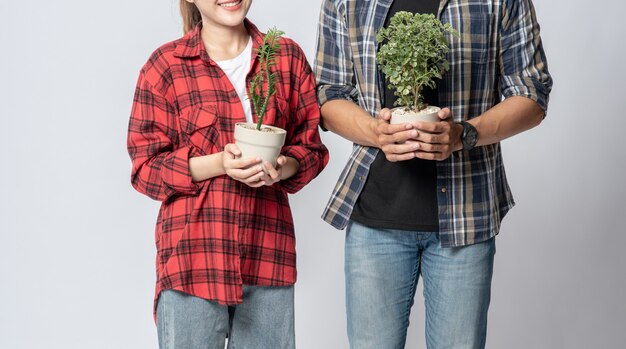 Photo gratuite hommes et femmes debout et tenant des pots de fleurs dans la maison