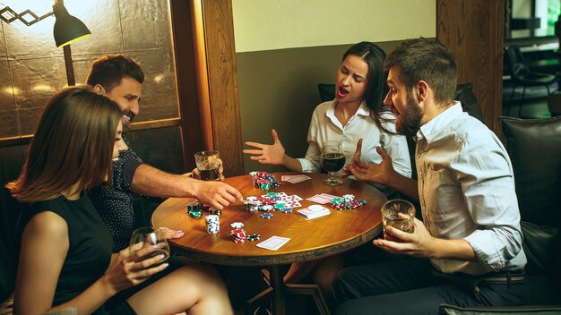 Hommes et femmes jouant au jeu de cartes. Poker, divertissement en soirée et concept d'excitation