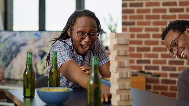 Hommes et femmes jouant avec des pièces de tour en bois sur la table, s'amusant avec des blocs carrés et des cubes en bois sur la construction de bâtiments. Jeunes profitant d'activités de loisirs passe-temps.