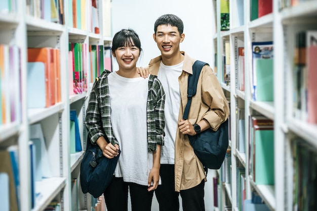 Hommes et femmes portant un sac à dos et recherchant des livres dans la bibliothèque.