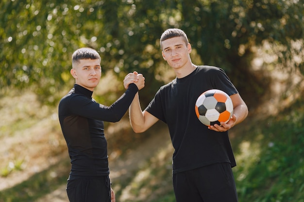 Les hommes jouent au socer au parc. Tournoi sur mini-footbal. Guy en tenue de sport noire.