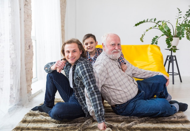 Hommes multigénérationnels assis sur un tapis à la maison