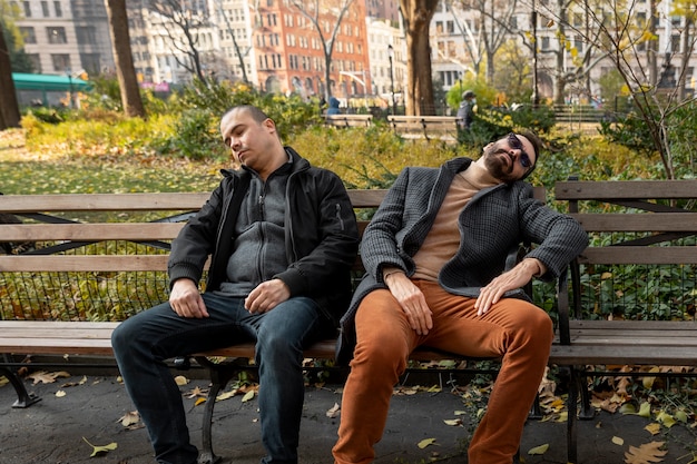 Hommes de plan moyen dormant sur un banc