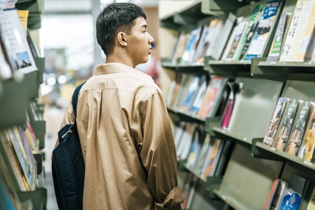 Des hommes portant un sac à dos et recherchant des livres dans la bibliothèque.