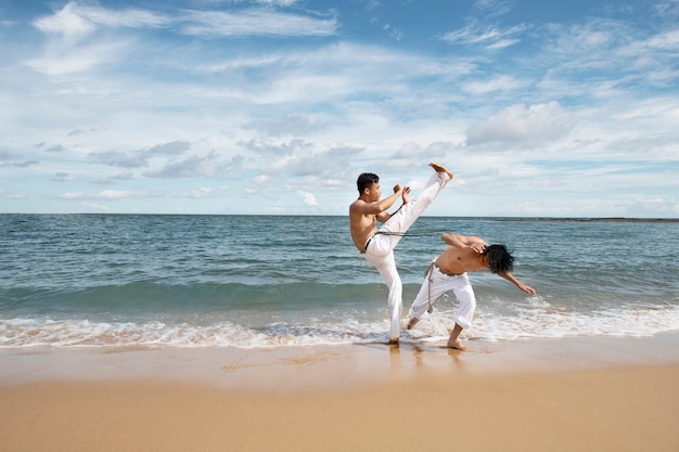 Photo gratuite hommes près de la plage pratiquant ensemble la capoeira